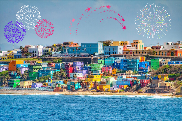 View of multi-colored buildings with the ocean in the foreground. There are also fireworks in the sky during the day, which isn't legitimate but here we are.