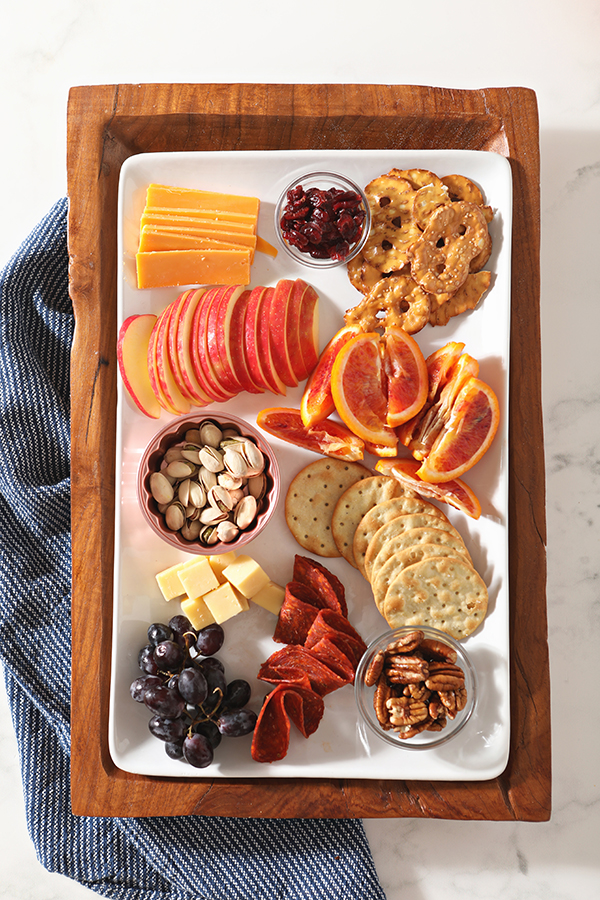 A completed cheese board with fall fruits, nuts, pepperoni and more from above