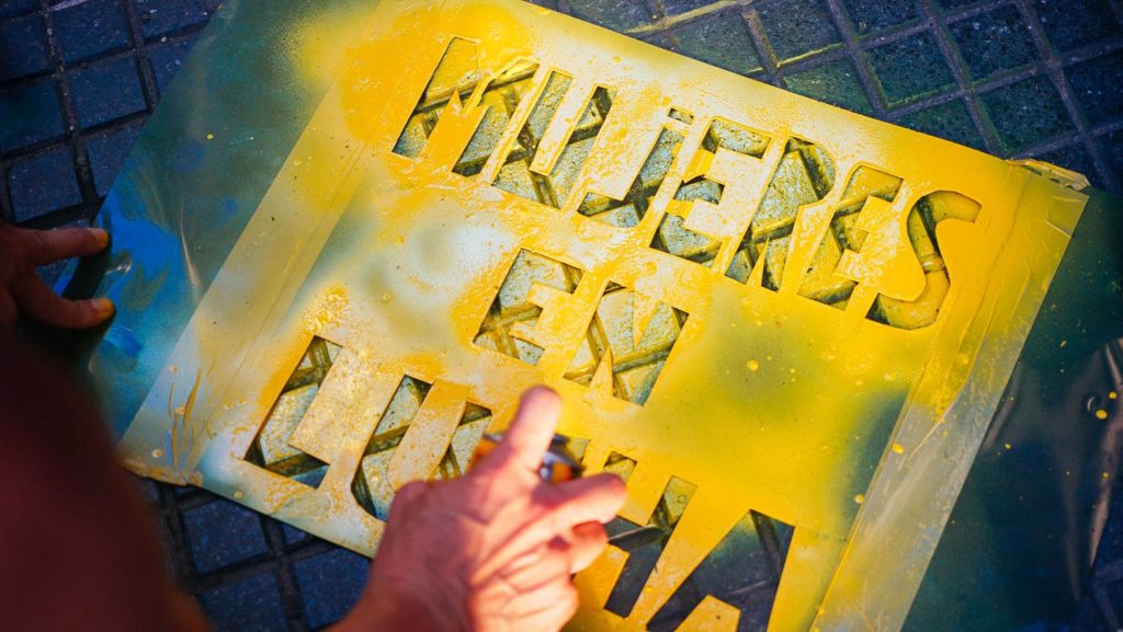 spray paint stencil with the words "mujer en la lucha" or "women in the fight" in spanish