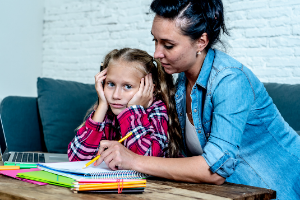 Caregiver sitting with a young child who is disinterested in learning what the caregiver is attempting to teach.