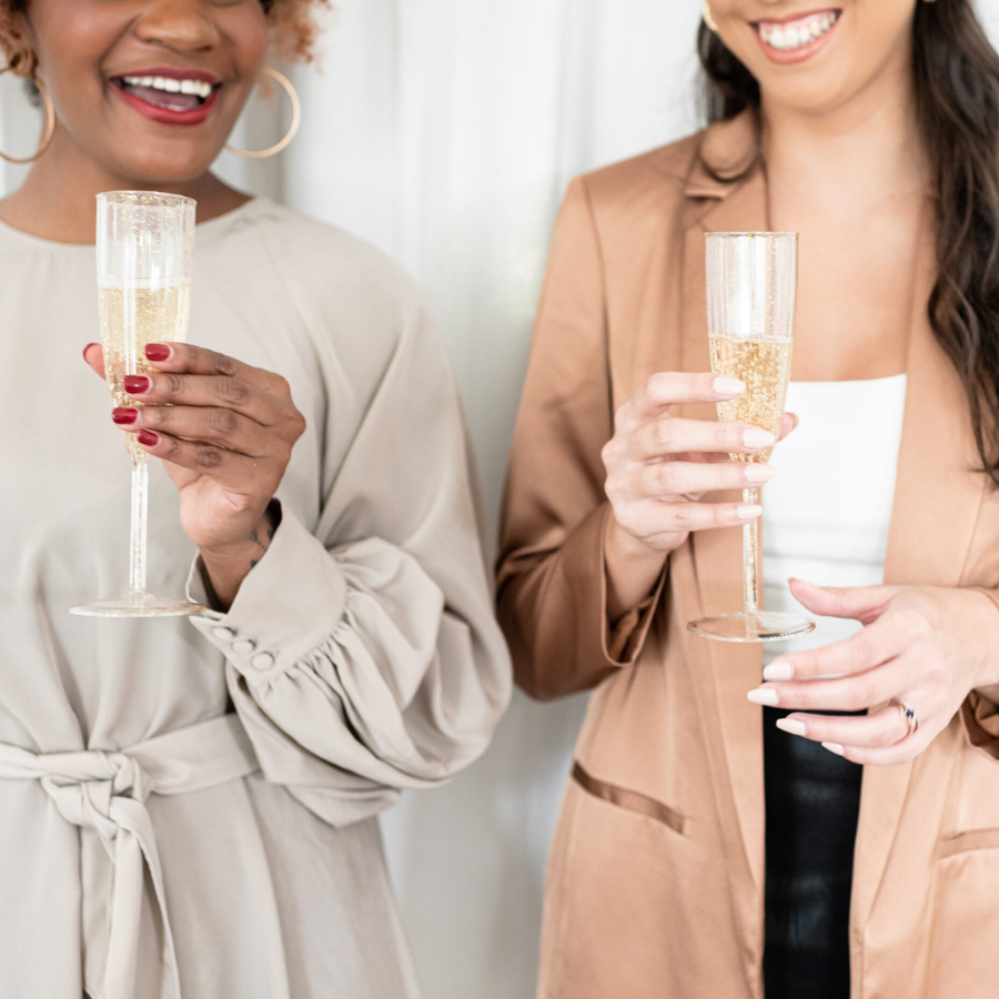 two women at a holiday party drinking champagne