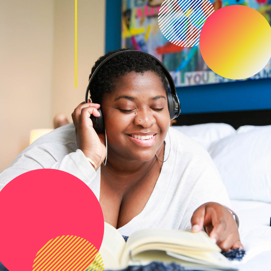 12 Books That Are Pure Joy - Black woman with headphones on reading in bed and smiling, surrounded by colorful, vibrant, decorative circles