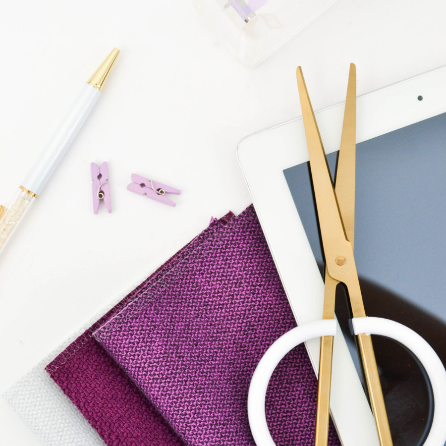 photograph of needlework supplies, including sewing scissors and fabric, in shades of white and purple