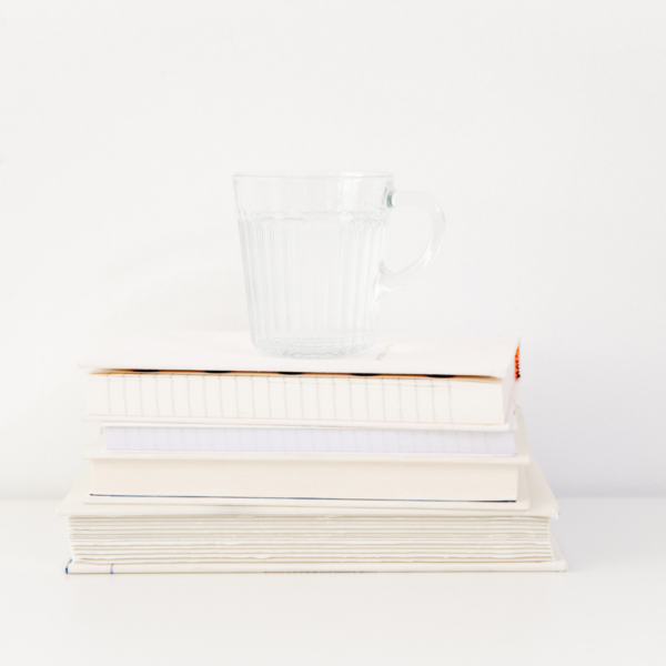 pile of books with a glass of water on top