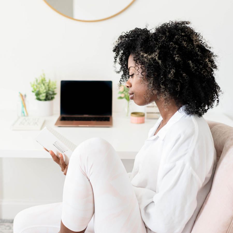 Black woman in all white reading a book