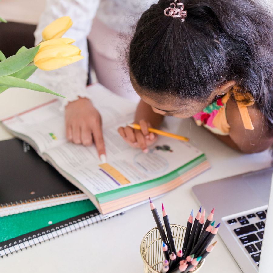 child bending over a school book while an adult helps