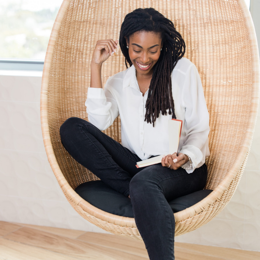 A Black woman sits in a chair reading