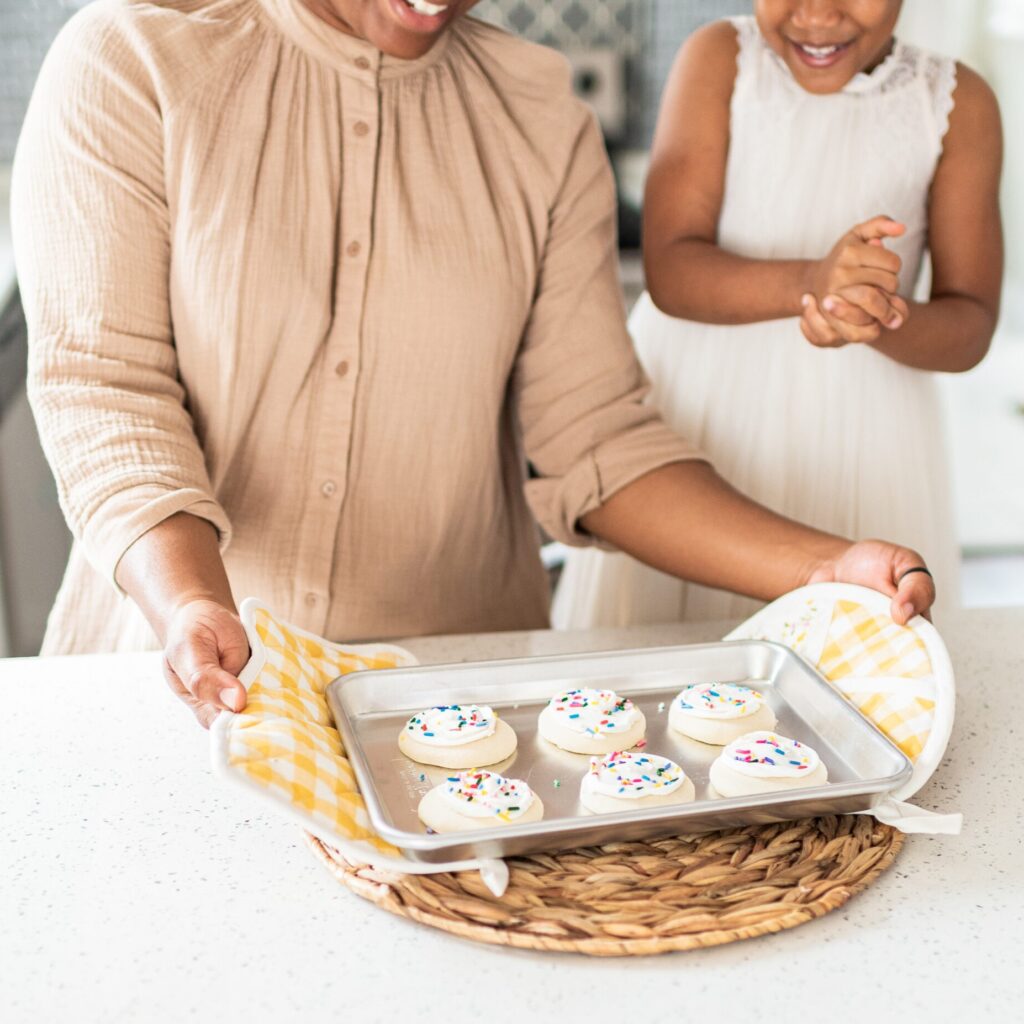 A parent and child set fresh cookies from the oven onto the counter top. This image is just decorative to show that we're discussing our favorite cookbooks!