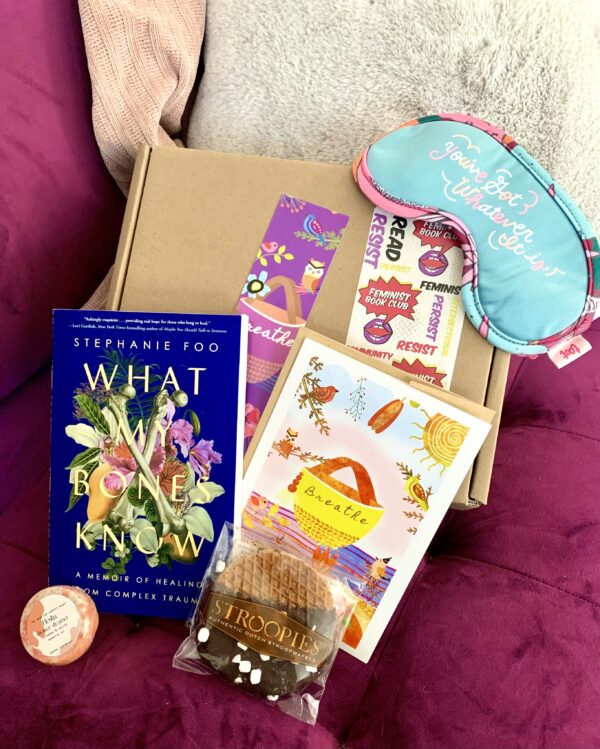 Feminist Book Club's May box with all the contents displayed on a couch.