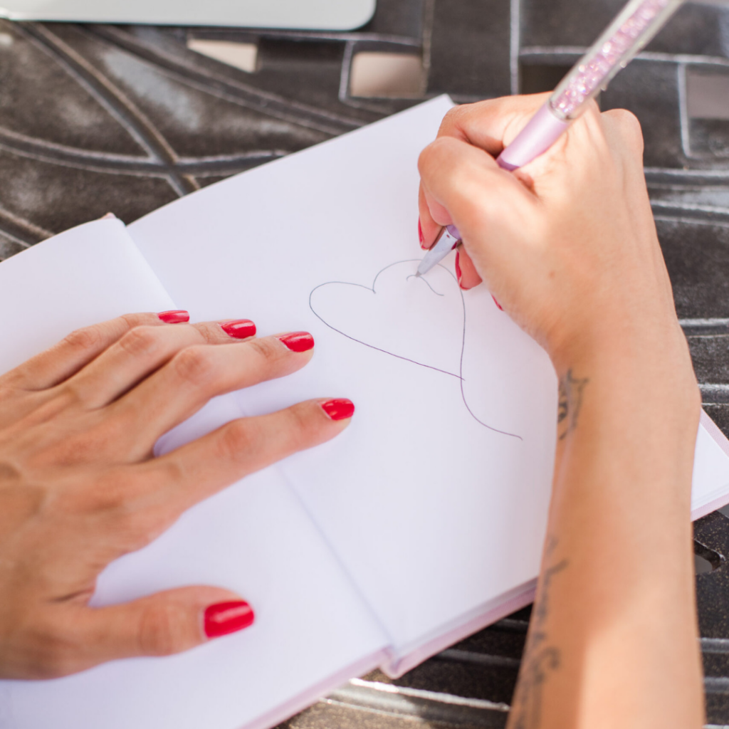 Person drawing a heart in a notebook as she thinks about Blind Data Webcomic and Stone Blind by Natalie Haynes