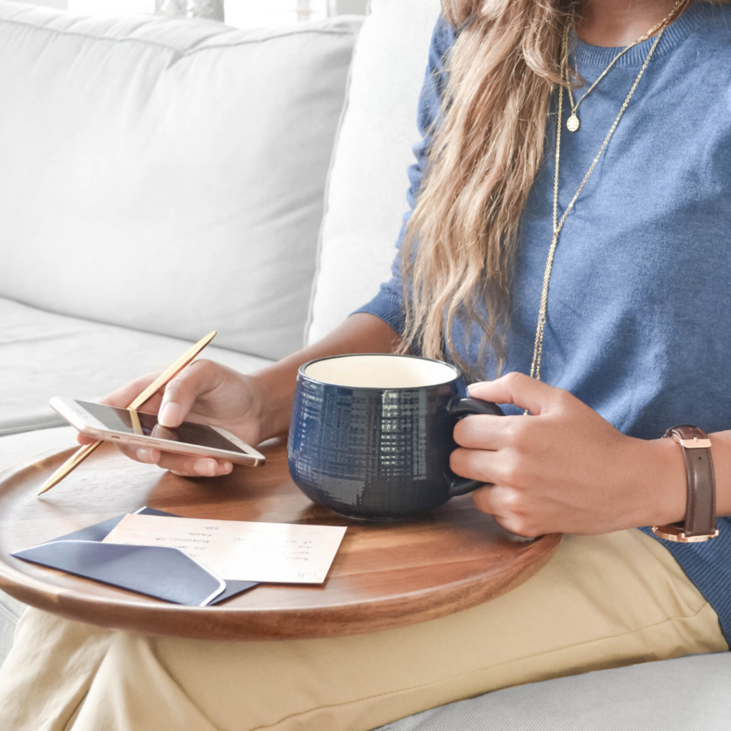 A person is on their phone while holding a cup of coffee.